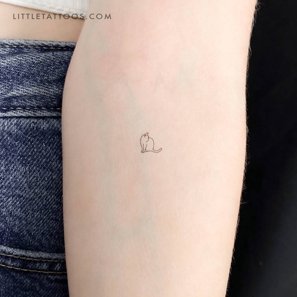 Tiny fine line cat temporary tattoo located on the inner forearm.