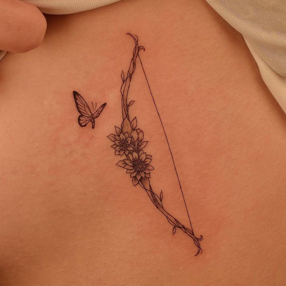 Fine line floral bow tattoo on the side boob.