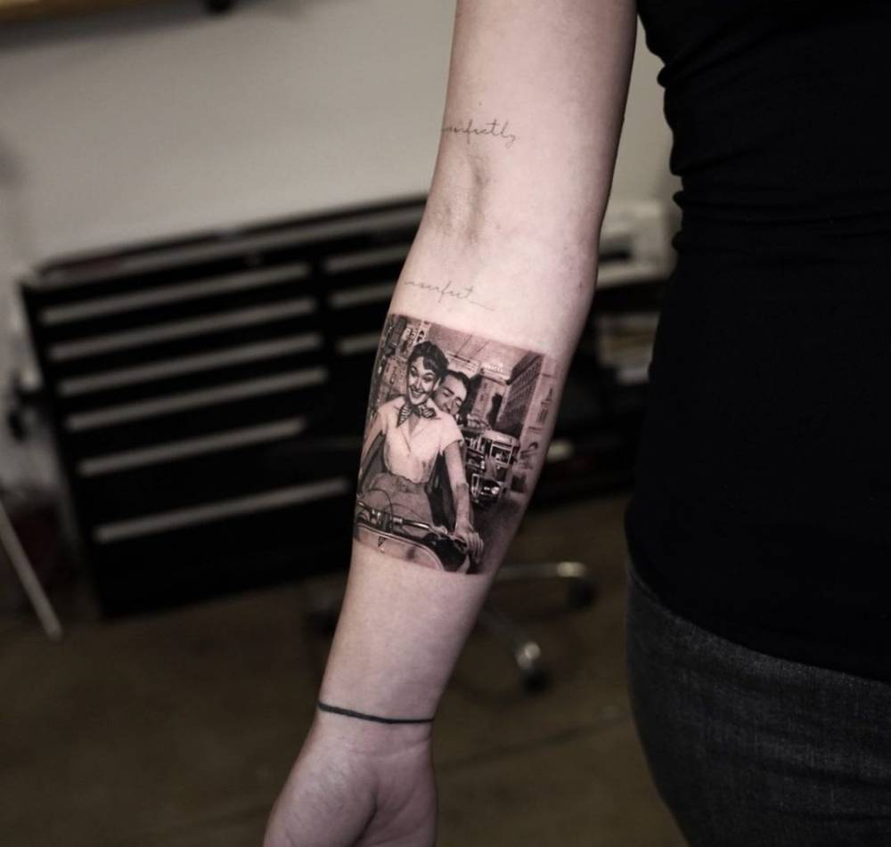 Micro-realistic Roman Holiday tattoo on the inner forearm.