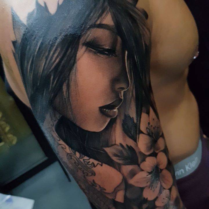 Black and grey geisha tattoo on the upper arm.