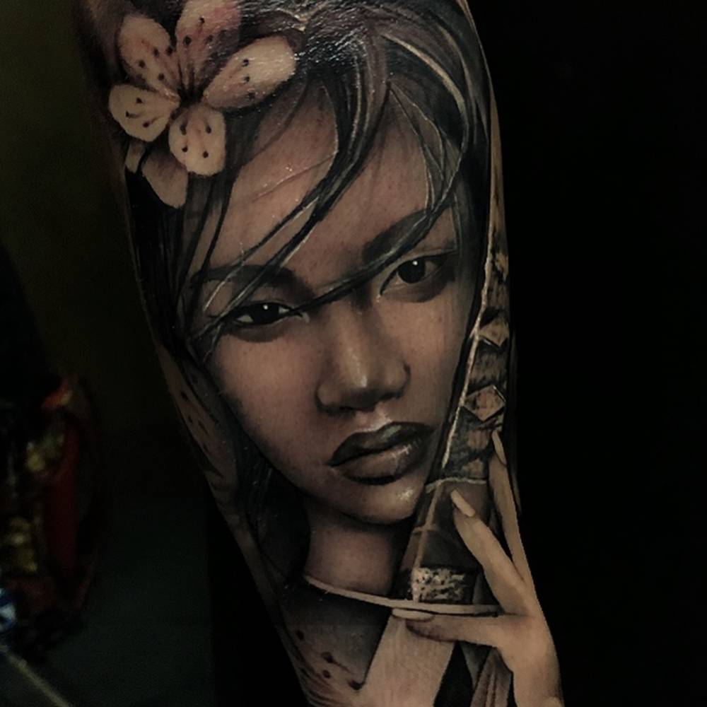 Black and grey Onna-bugeisha tattoo on the inner forearm.
