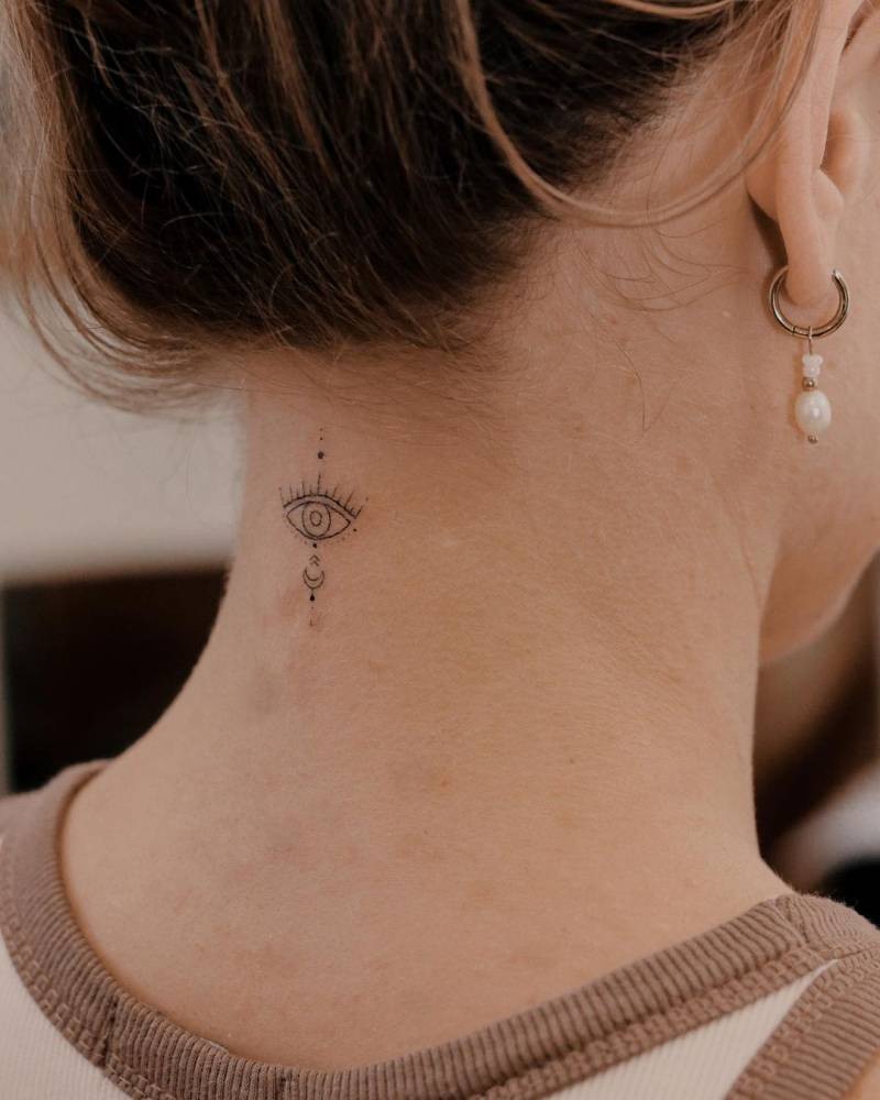 Fine line style evil eye tattoo placed on the back of the neck.
