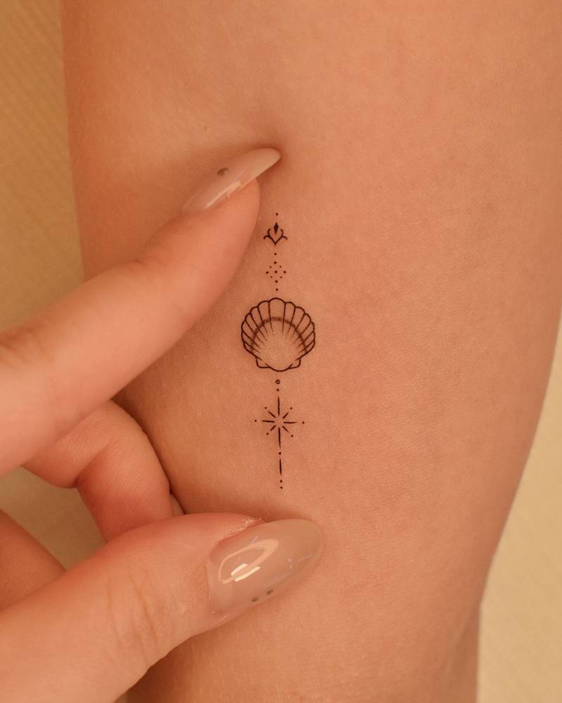 Ornamental scallop shell tattoo located on the inner arm.