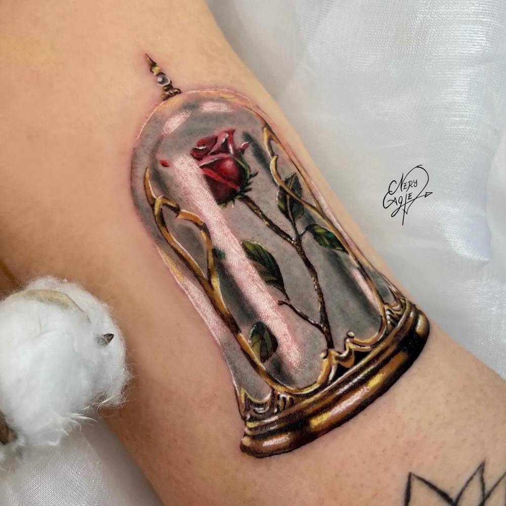 Realistic style rose in a glass dome tattoo located on the inner arm.