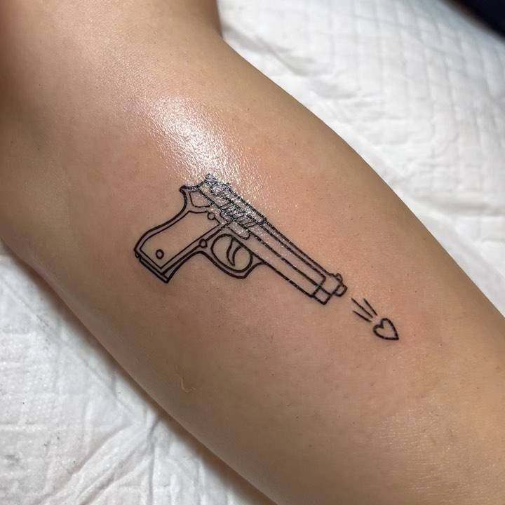 Line art gun tattoo located on the forearm.