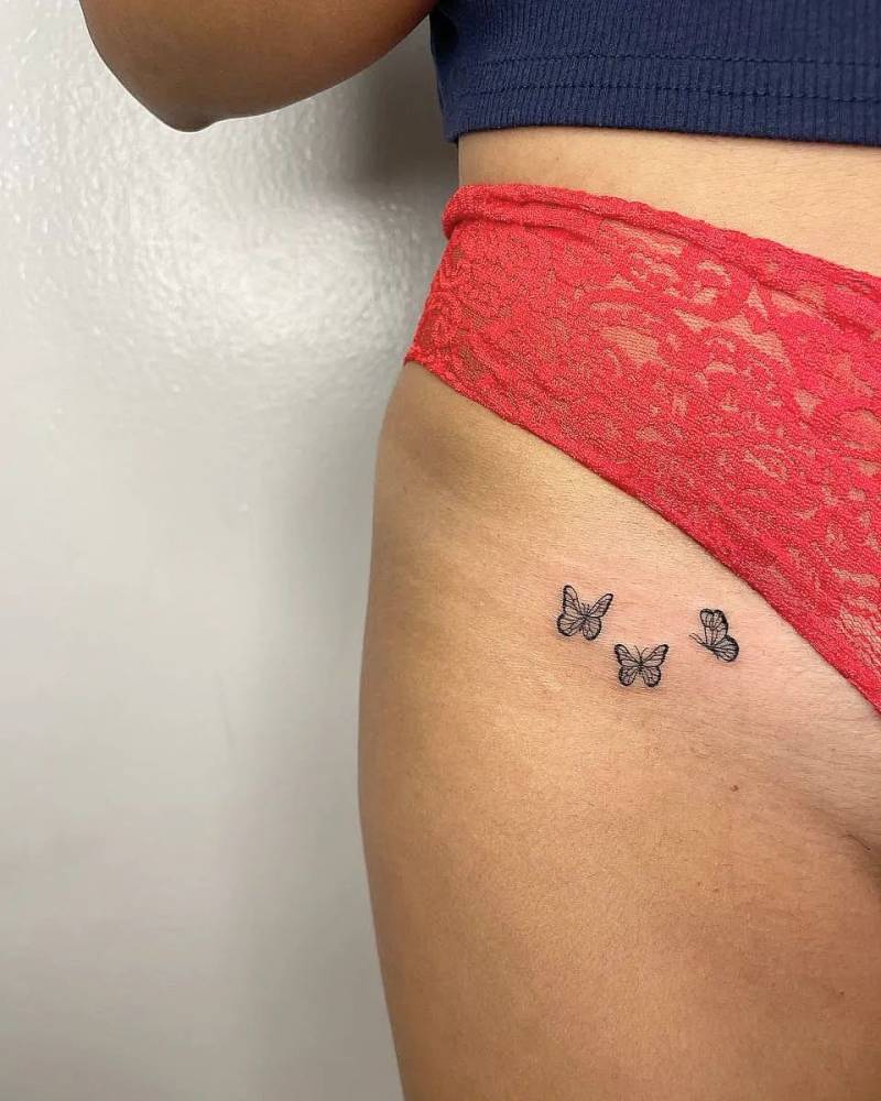 Fine line butterflies tattooed on the pelvis.
