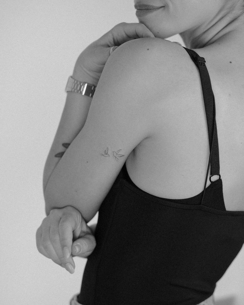 Continuous line flying birds tattoo located on the tricep.