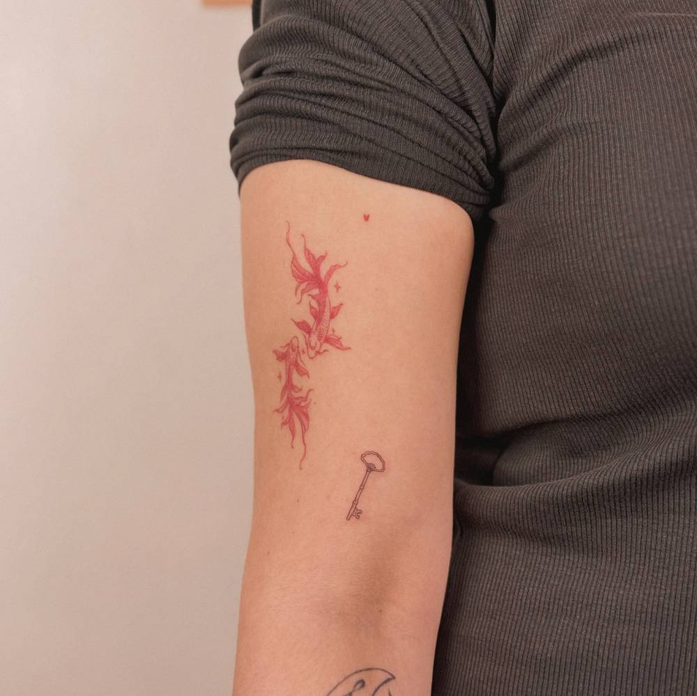 Fine line style key tattoo located on the bicep.