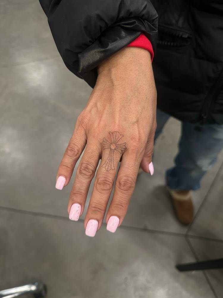 Cross tattoo in fine line style located on the finger.