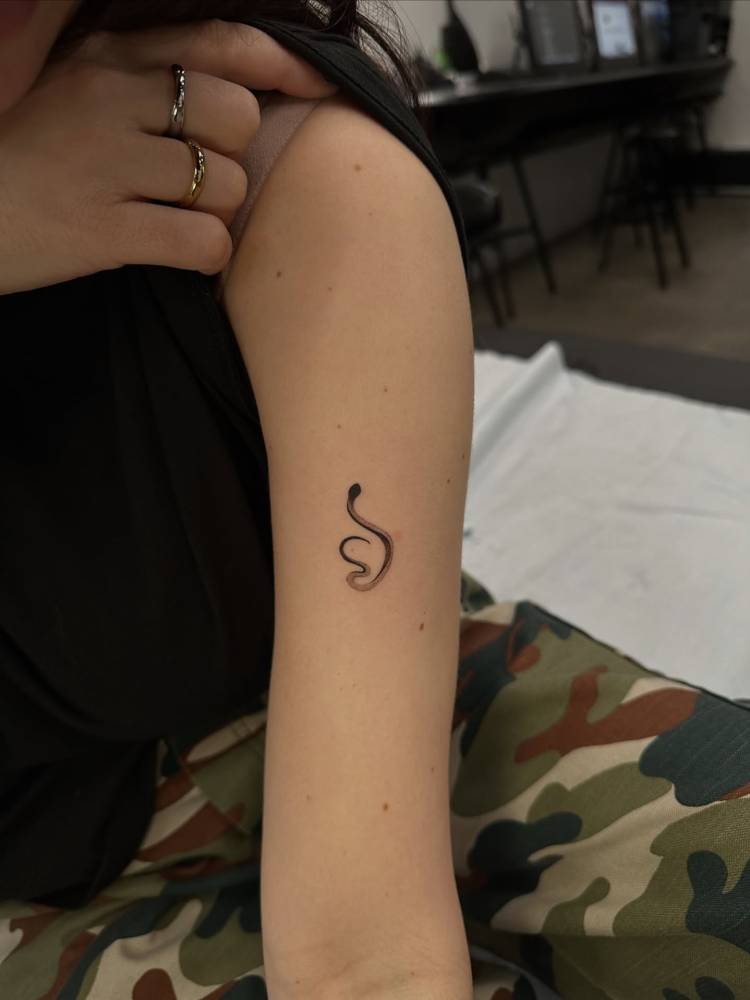 Little snake tattoo in illustrative style done on the upper arm.