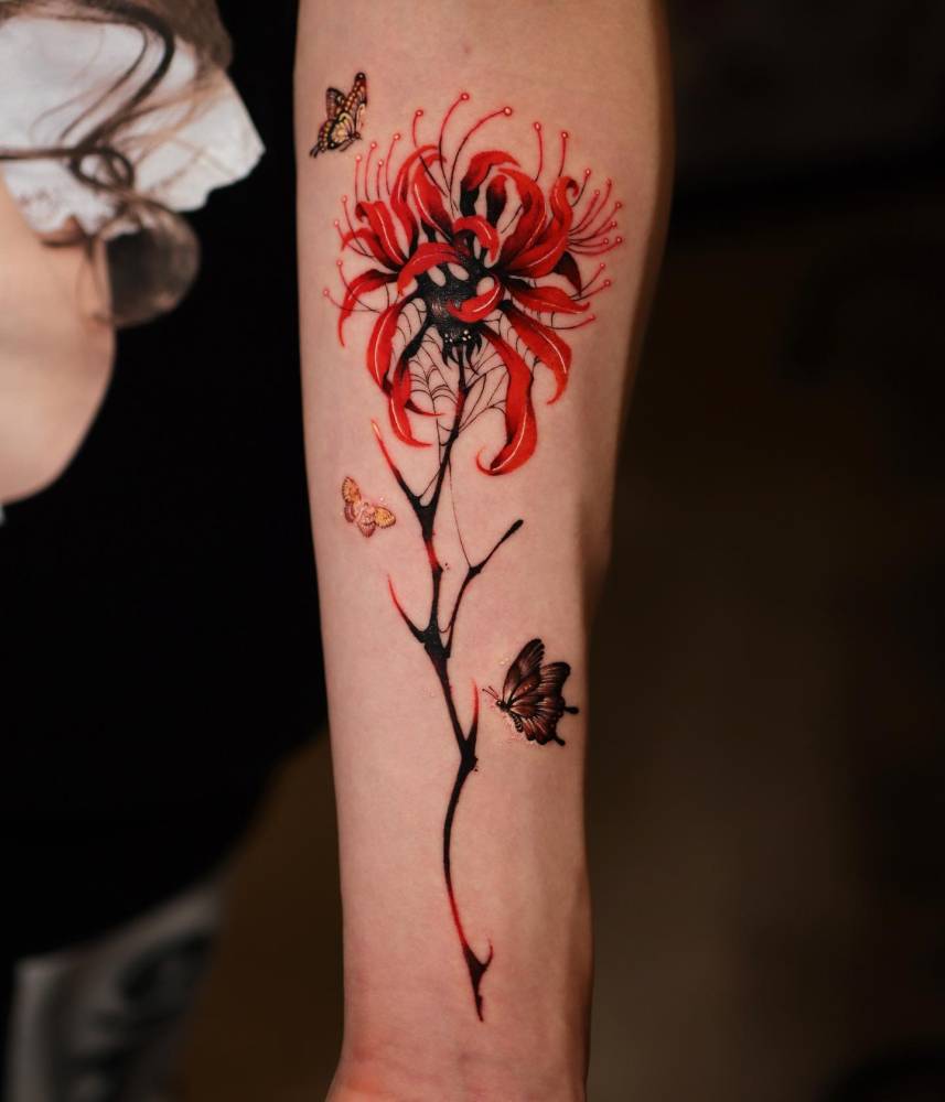 Red spider lily tattoo located on the inner forearm, illustrative style.