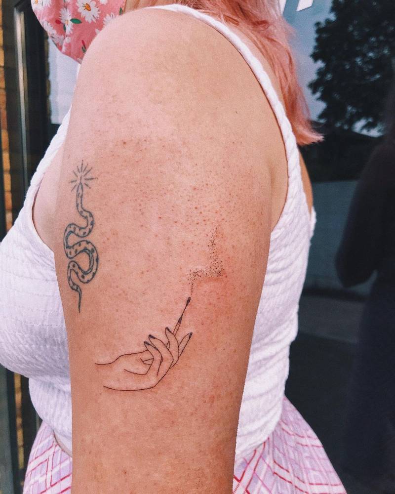 Hand poked hand holding a matchstick and a sneaky healed snake tattoos.