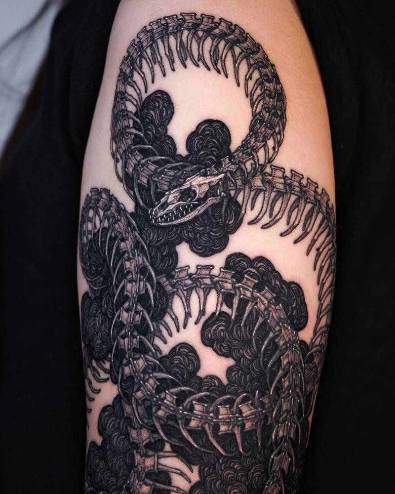 Blackwork style skeleton snake tattoo done on the upper arm.