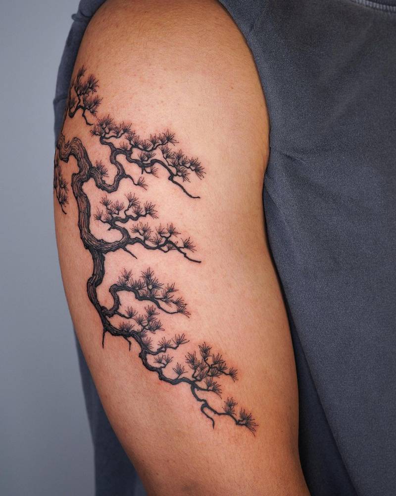 Tree branches tattoo located on the upper arm, illustrative style.