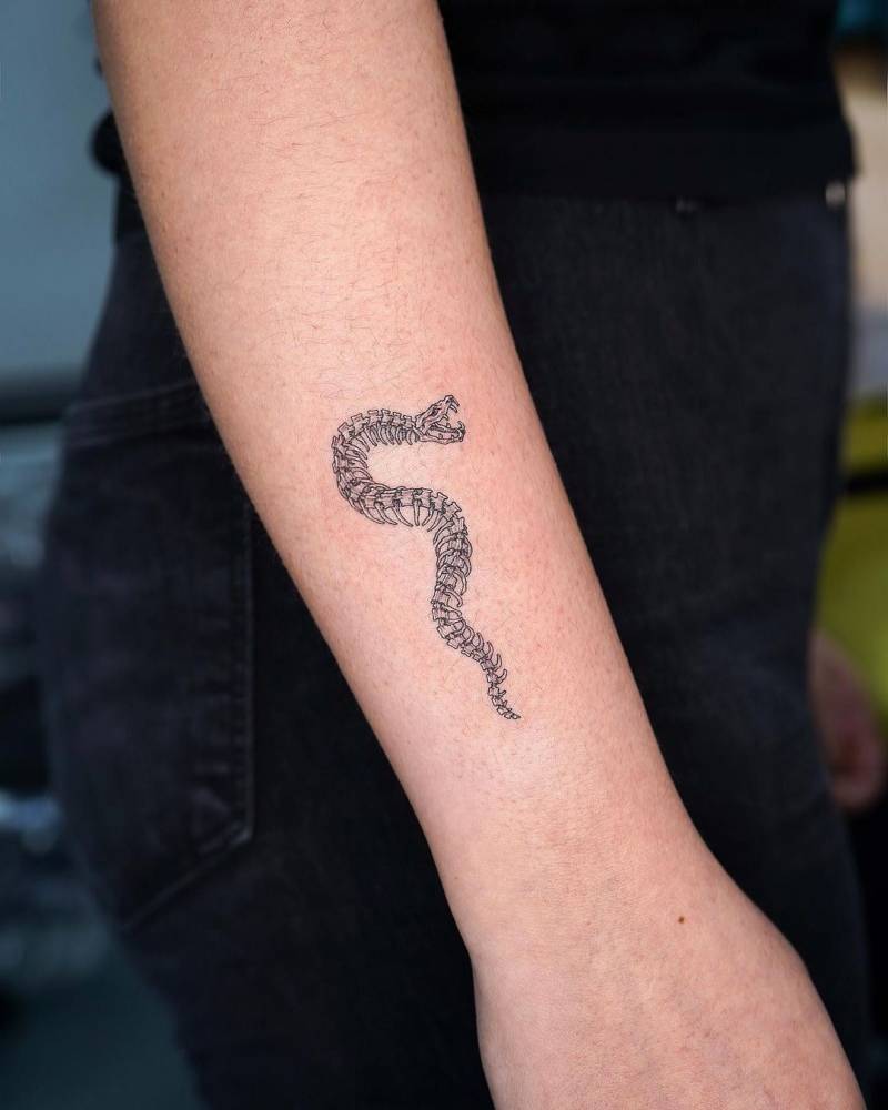 Small skeleton snake tattooed on the forearm.