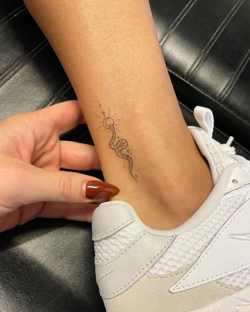 Fine line snake tattoo located on the ankle.