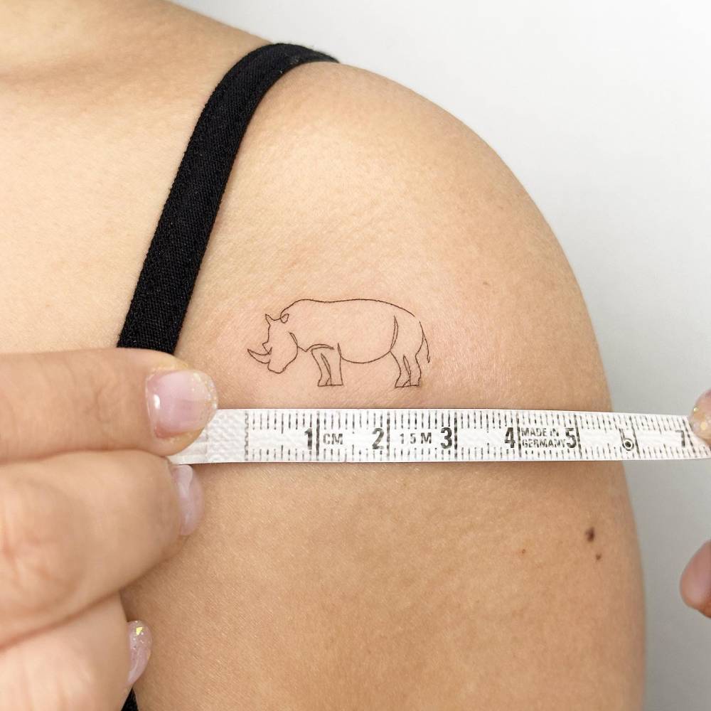 One line rhino tattoo placed on the shoulder.