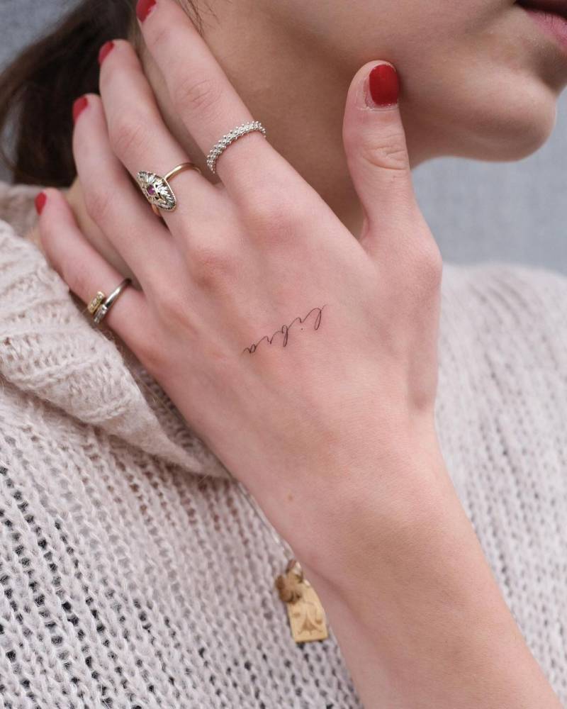 Tattoo of the word "libra" handwritten on the hand.