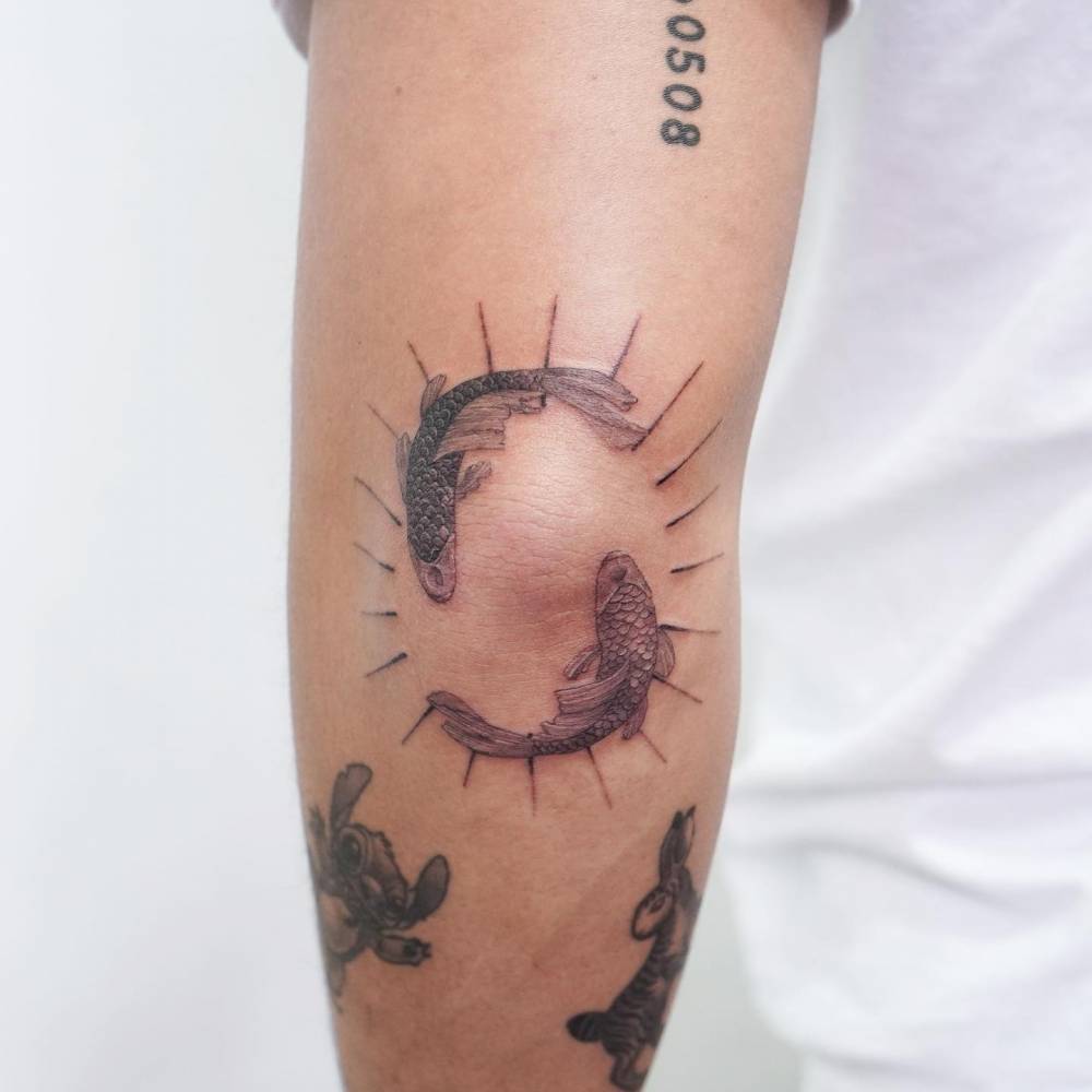 Two opposite carps tattooed on the elbow.