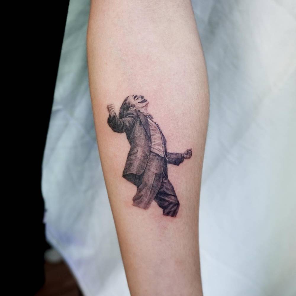 Joker tattoo located on the inner forearm, micro-realistic style.