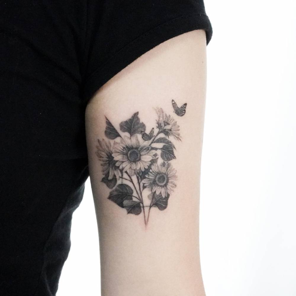 Sunflower tattoo located on the tricep, micro-realistic style.