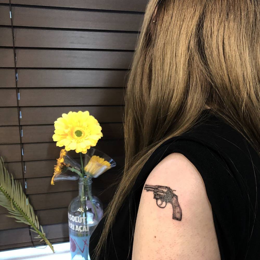 Micro-realistic style revolver tattoo done on the upper arm.