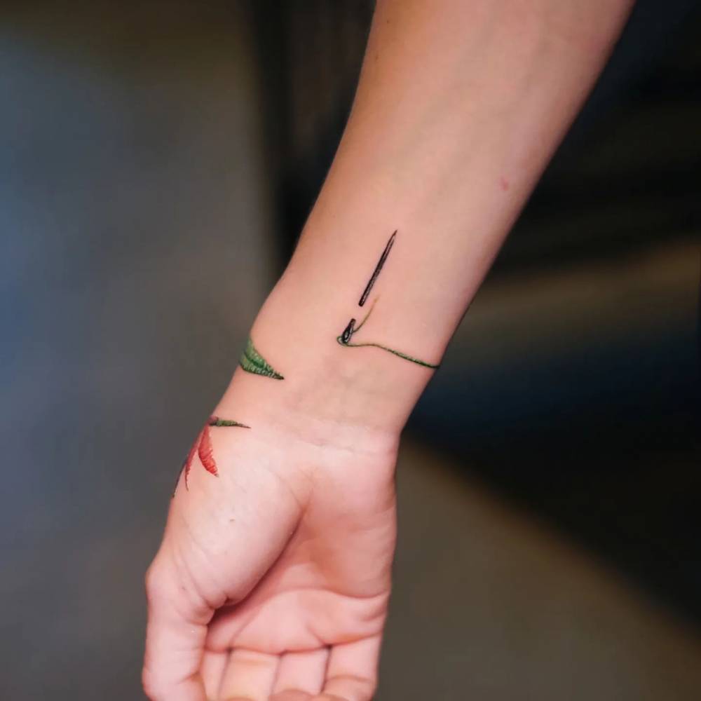 Needle tattoo located on the wrist, embroidery style.