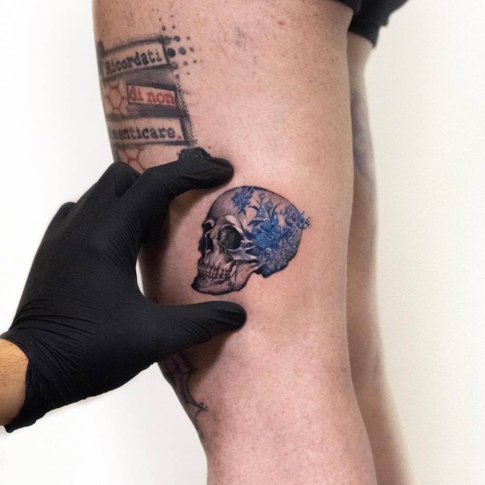 Porcelain skull tattoo located on the thigh.
