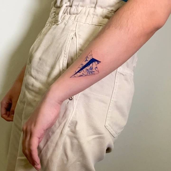 Porcelain paper airplane tattoo located on the forearm.