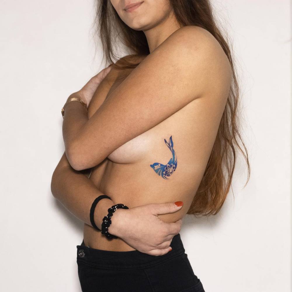 Porcelain dolphin tattoo located on the side boob.