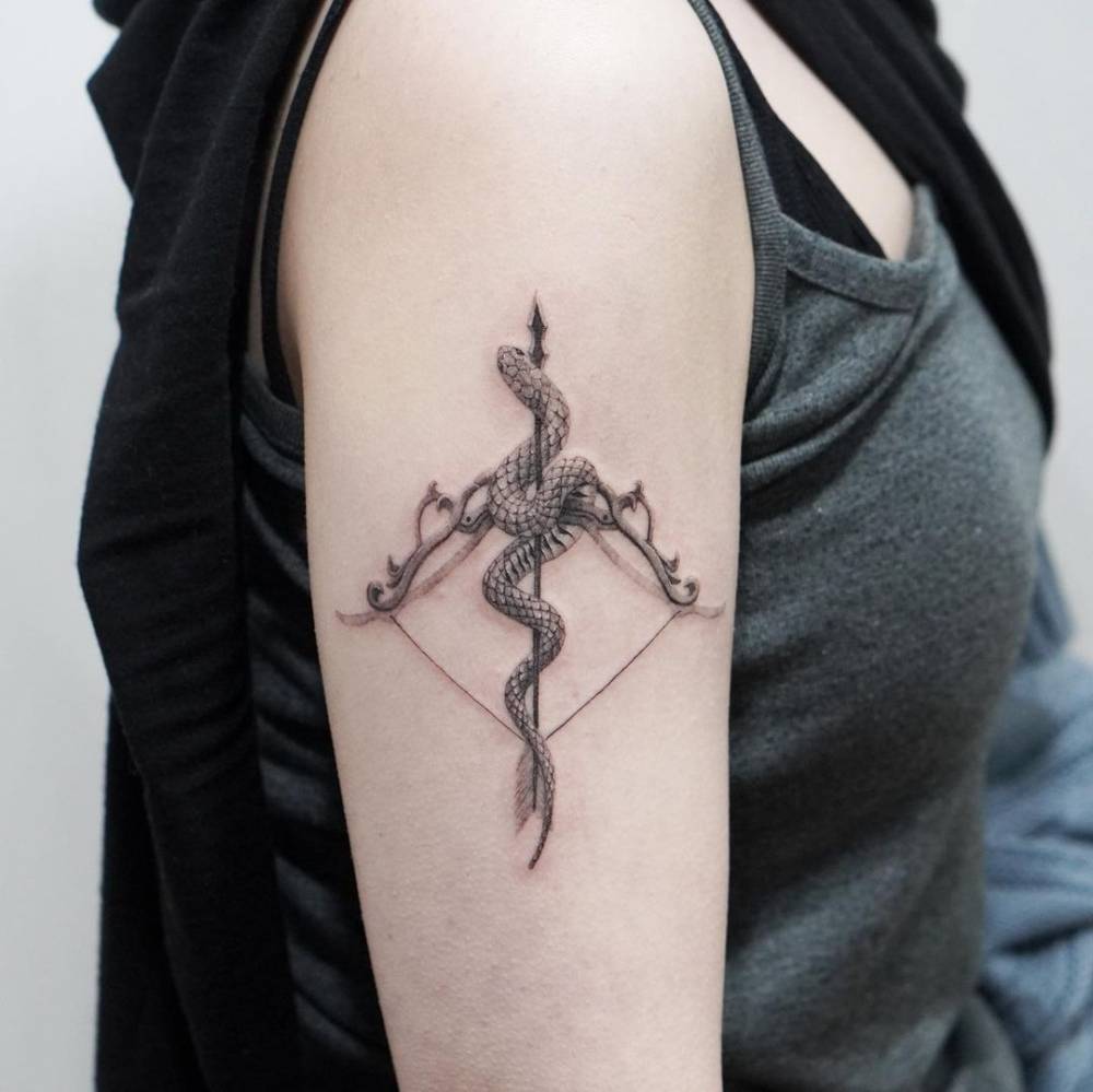 Micro-realistic bow, arrow and snake tattoo located on the upper arm.