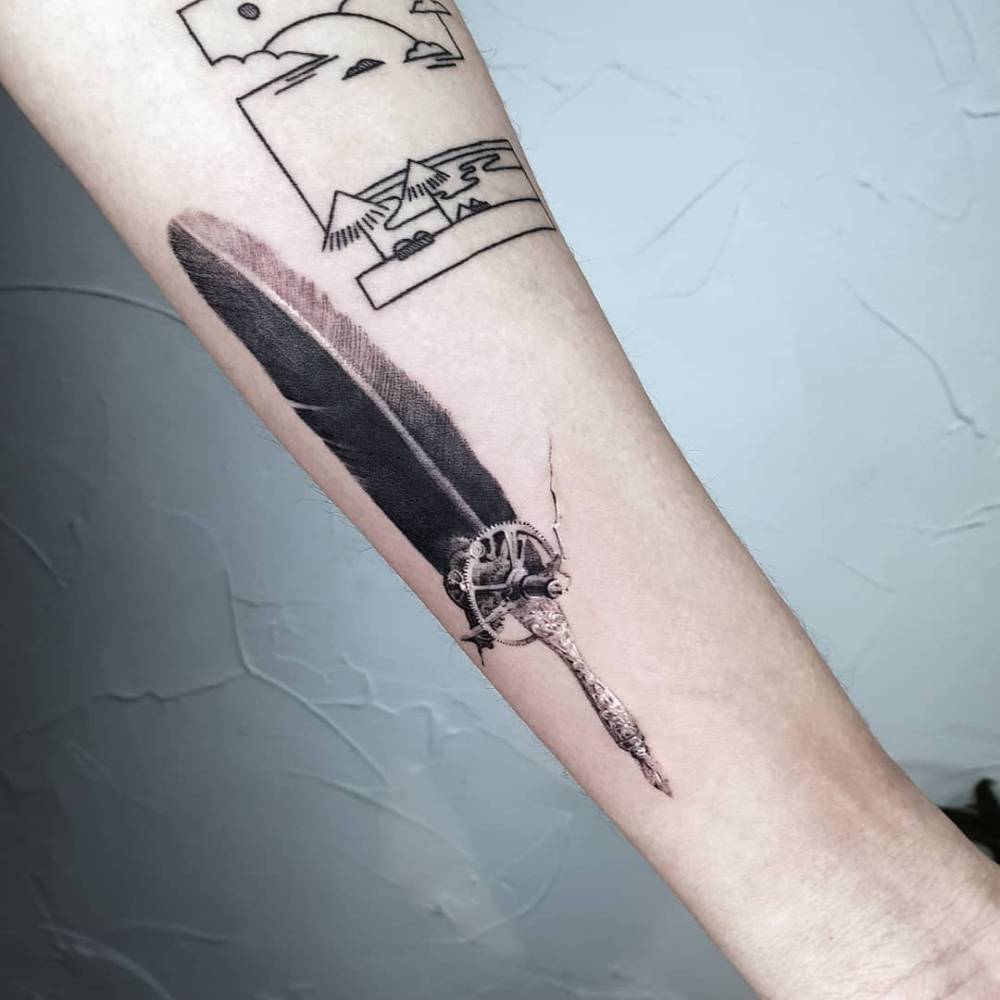Micro-realistic style quill pen tattoo located on the inner forearm.