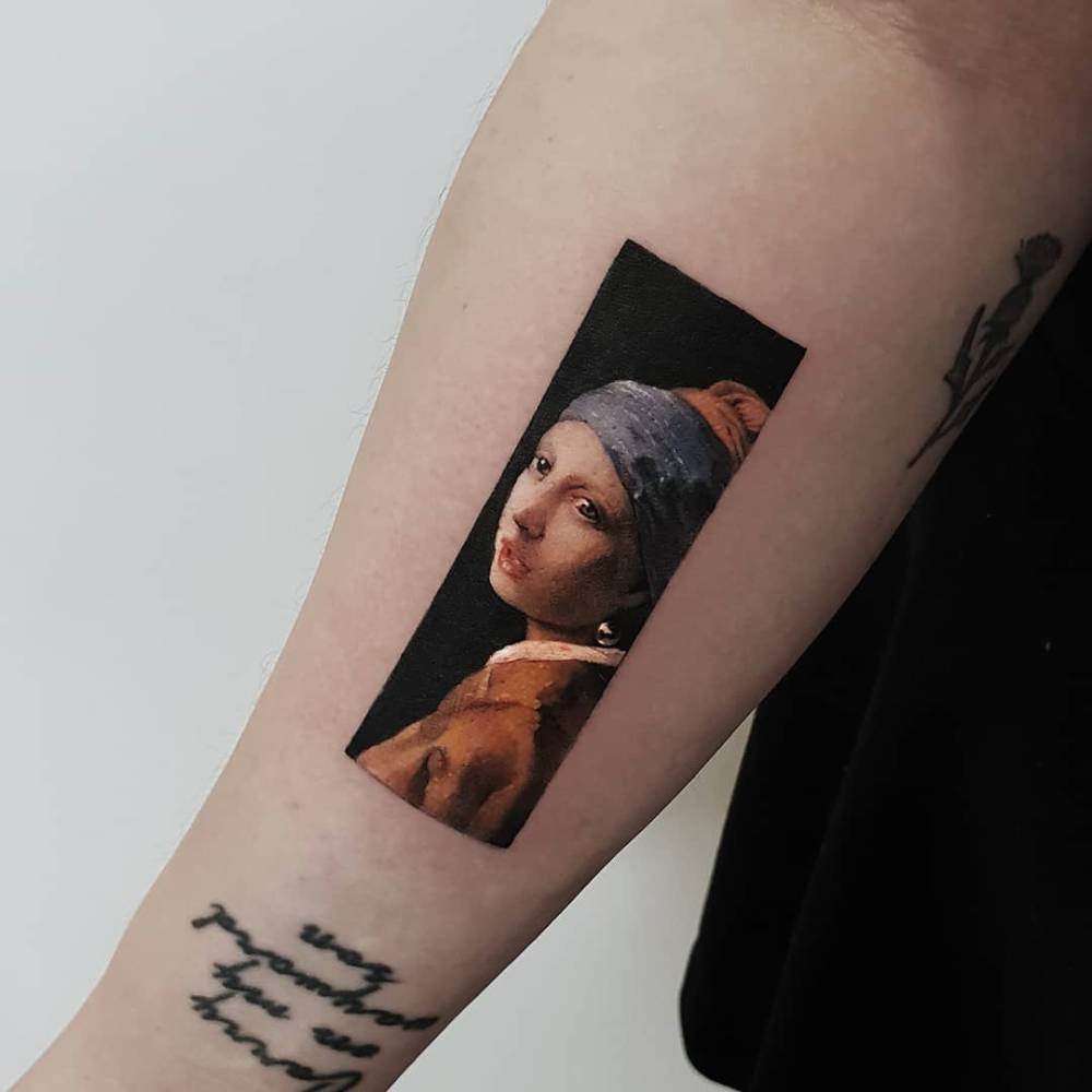 'Girl with a Pearl Earring' tattoo located on the inner forearm.