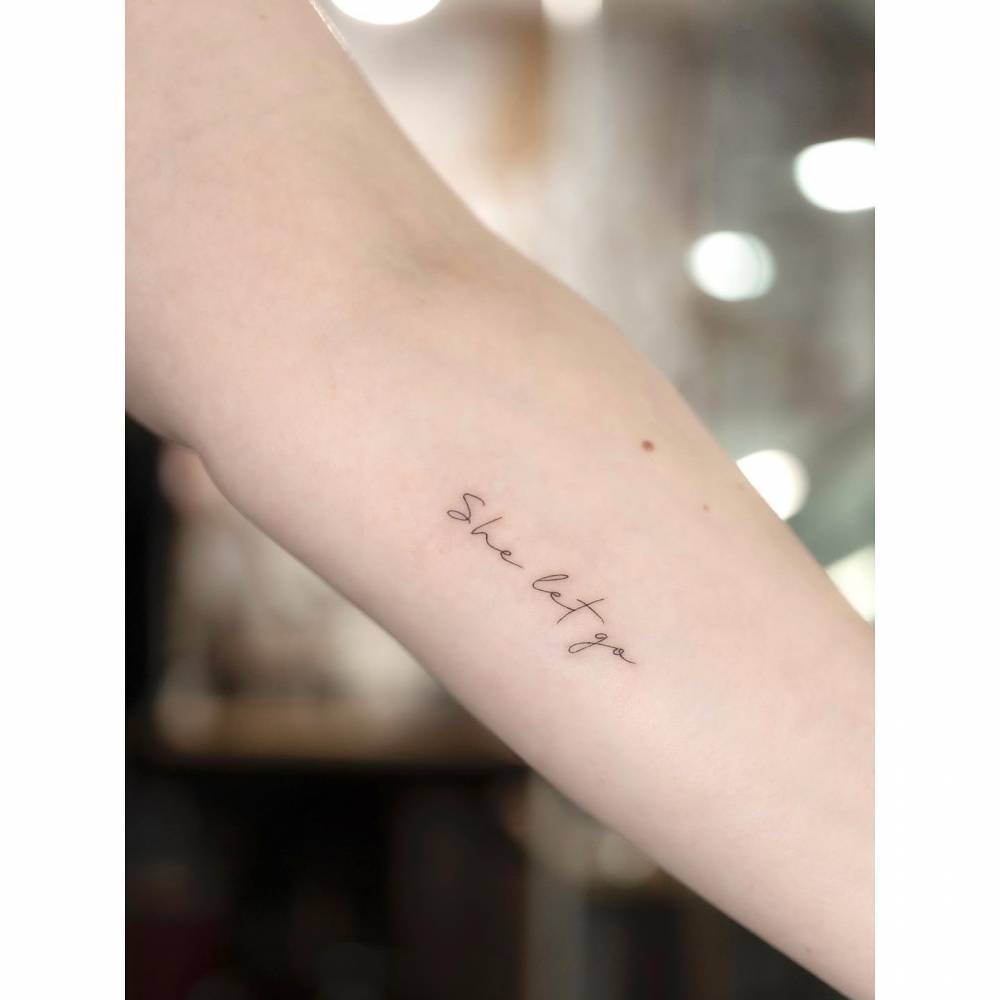 "She let go" lettering tattoo done on the inner forearm.