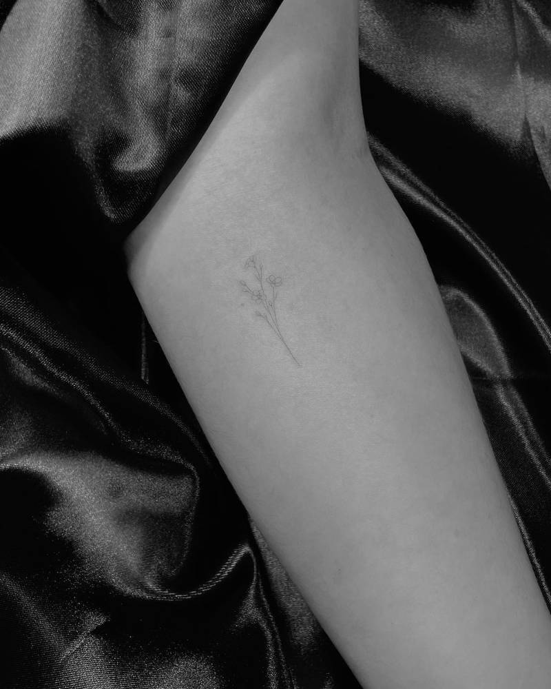 Fine line style forget-me-not tattoo located on the forearm.