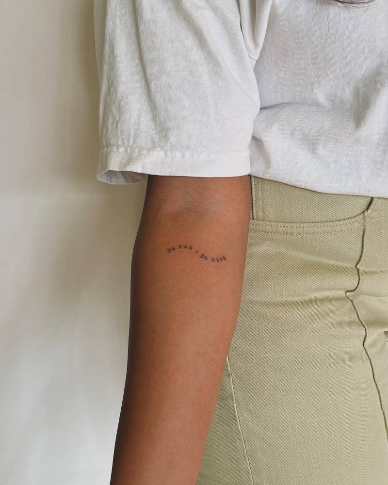 "So far, so good" lettering tattoo hand poked on the inner forearm.