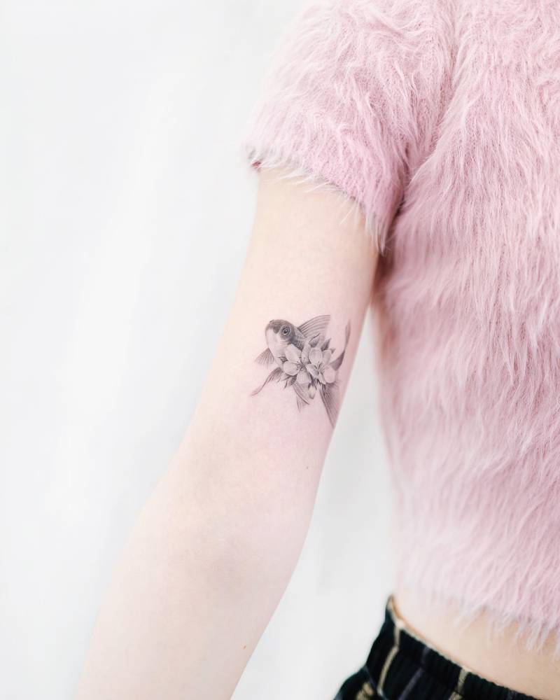 Single needle floral fish tattooed on the tricep.