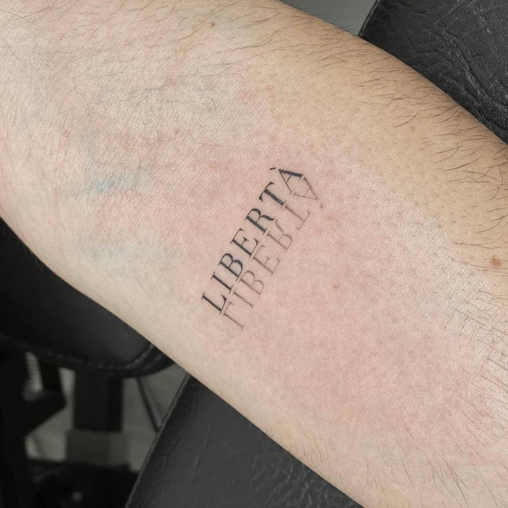 "Libertà" mirror writing tattoo located on the inner forearm.