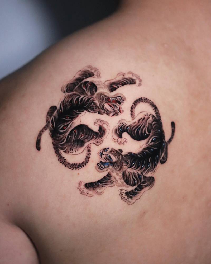 Tigers tattoo in oriental style located on the shoulder blade.