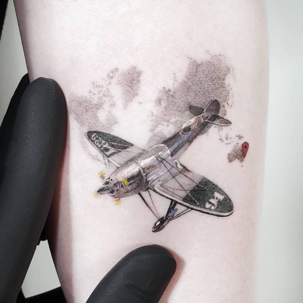 Plane tattoo in watercolor style located on the inner forearm.