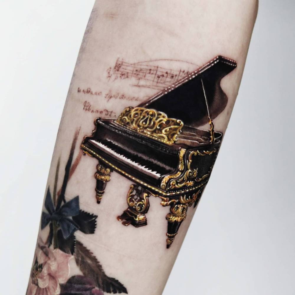 Micro-realistic style piano tattoo located on the inner forearm.