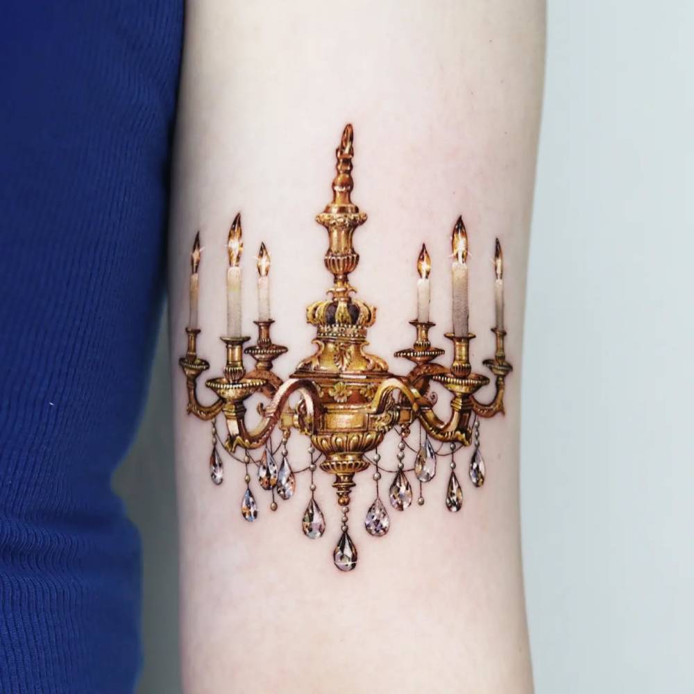 Chandelier tattoo placed on the bicep, done in micro-realism.