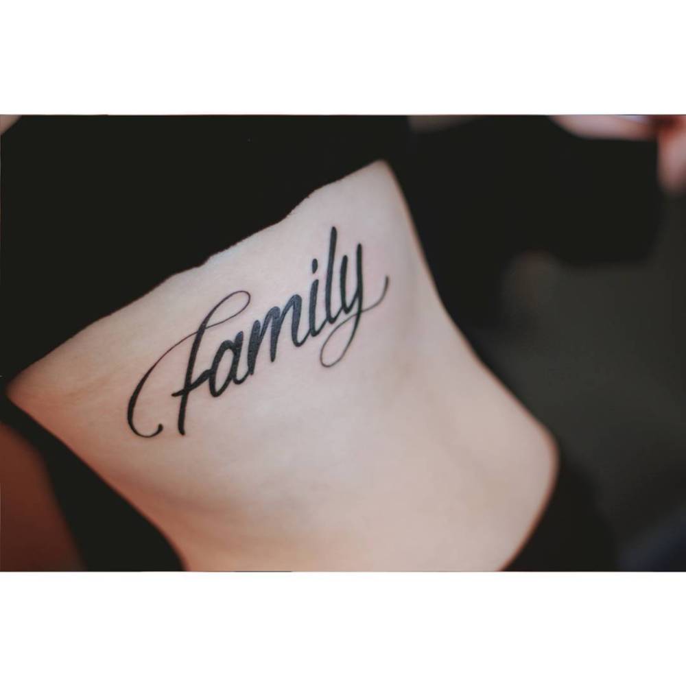 Word "family" in script font tattooed on the rib.