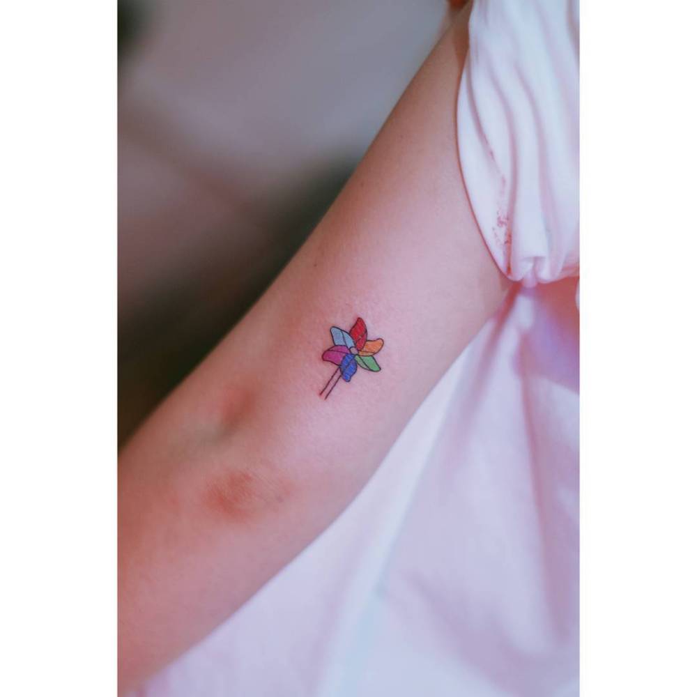 Illustrative style pinwheel tattoo located on the tricep.