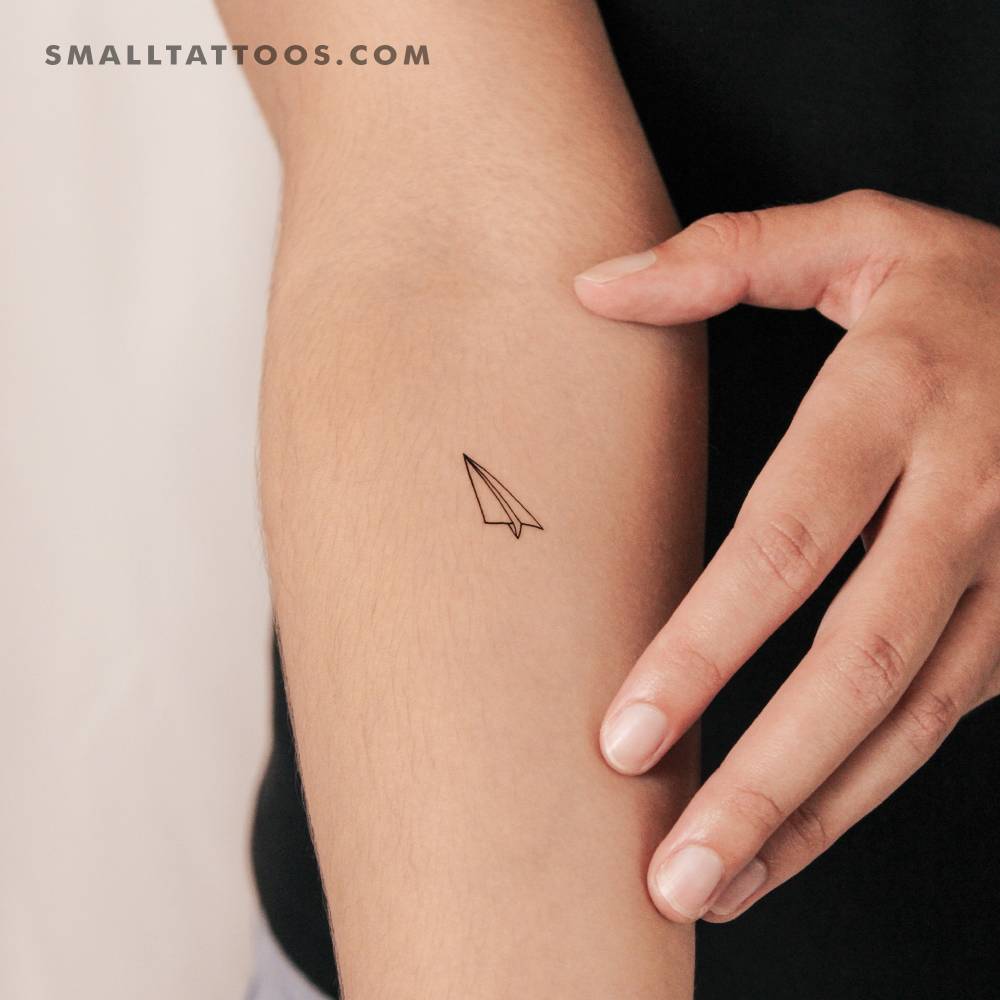 Minimalistic paper plane temporary tattoo located on the inner forearm.