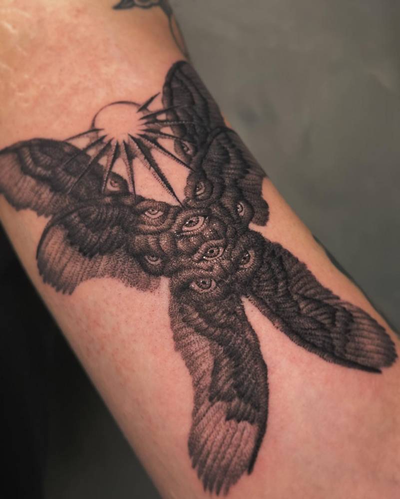 Six winged seraphim in blackwork style tattooed on the bicep.