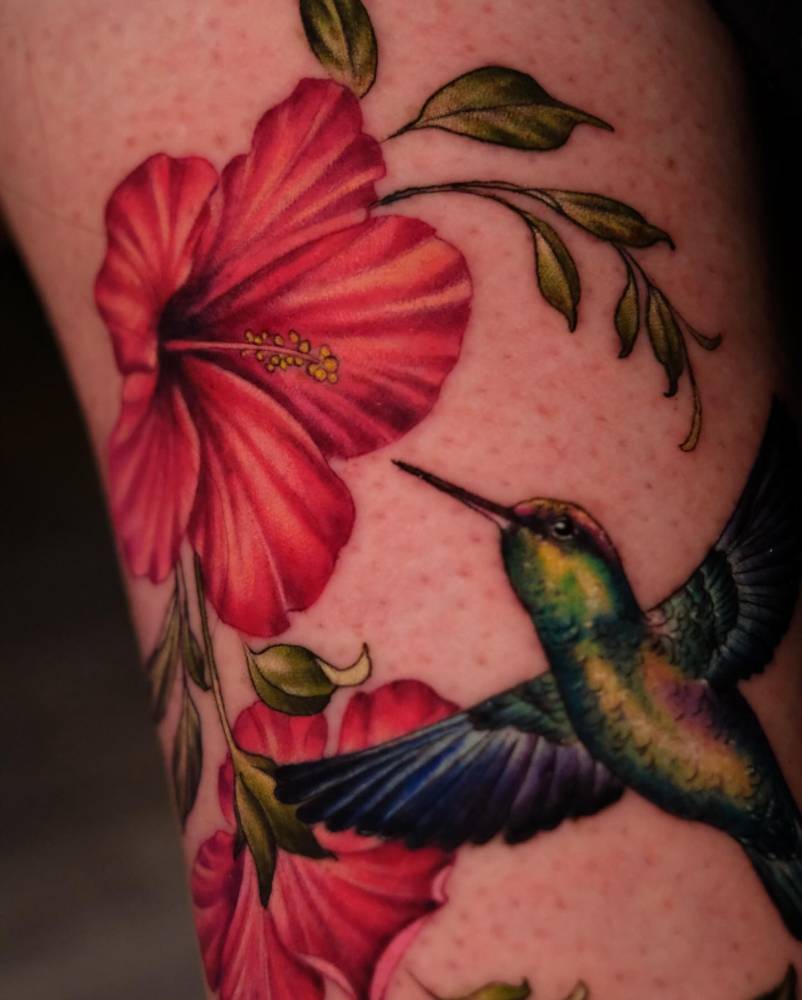 Illustrative style hummingbird and hibiscus tattoo located on the ankle.
