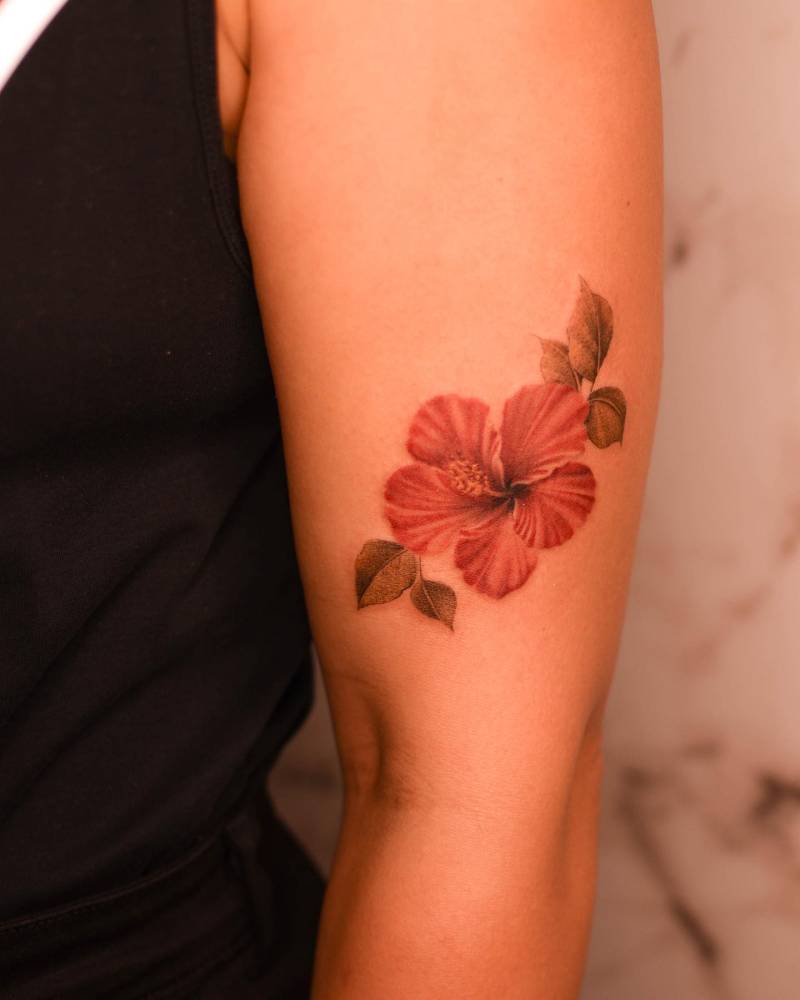 Watercolor style hibiscus tattoo placed on the upper arm.