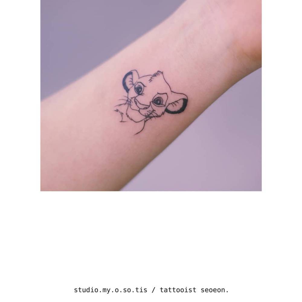 Simba portrait tattoo in cartoon style located on the wrist.