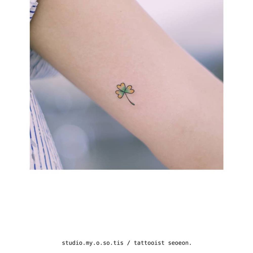 Three leaf clover tattoo done on the inner arm, illustrative style.